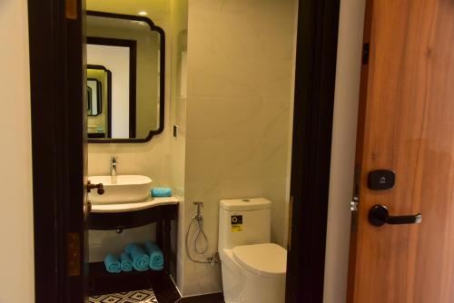 a bathroom with a toilet and a sink and a mirror at The Vista Beach Resort Phan Thiết in Phan Thiet