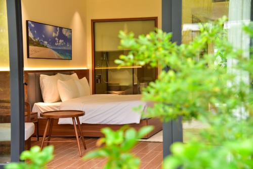 a bedroom with a bed and a table and a chair at The Vista Beach Resort Phan Thiết in Phan Thiet
