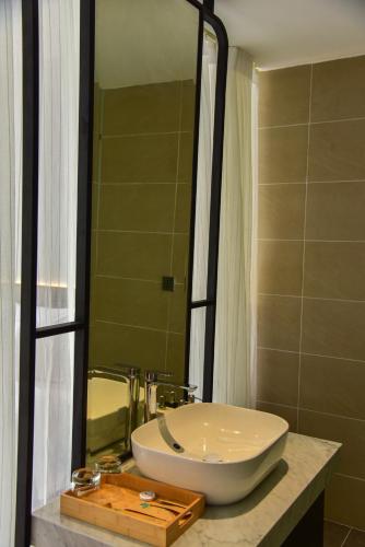 a bathroom with a white sink and a mirror at The Vista Beach Resort Phan Thiết in Phan Thiet