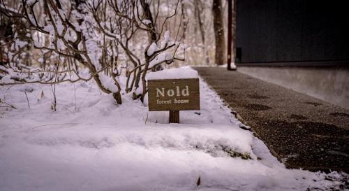 a sign in the snow on the side of a road at Nold forest house 那須高原の森の中で心地よく暮らす宿 in Nasu