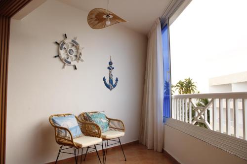 a balcony with two chairs and a clock on the wall at Albatros by R&R 2 in Villas del Mar