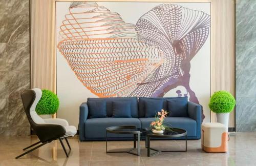 a living room with a blue couch and a painting at Echarm Hotel Chengdu Dujiangyan Scenic South Bridge in Chengdu
