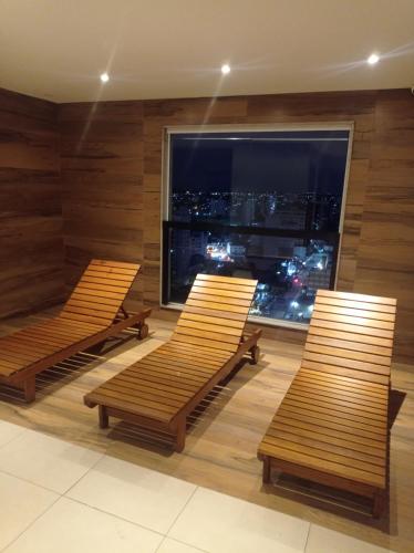 three benches in a room with a large window at Flat temporada in Campos dos Goytacazes