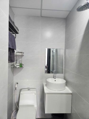 a white bathroom with a toilet and a sink at Eco BMT LUXURY HOTEL in Buon Ma Thuot