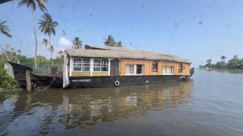 a house boat sitting in the water with at Alleppey Houseboat Viswas Cruise in Alleppey