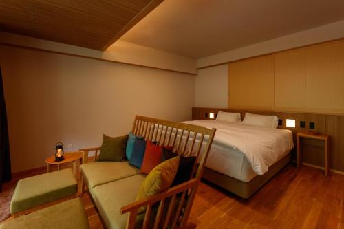 a bedroom with a bed and a couch at Sakunami Onsen Yuzukushi Salon Ichinobo in Sendai