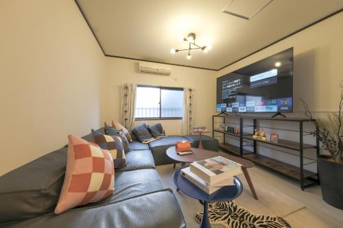 a living room with a blue couch and a tv at サンライズ田端新町ハウス in Tokyo