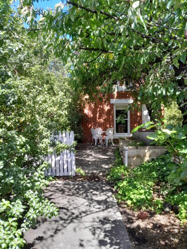 a garden with a white fence and a house at Annies Garden Cottage in Hobart