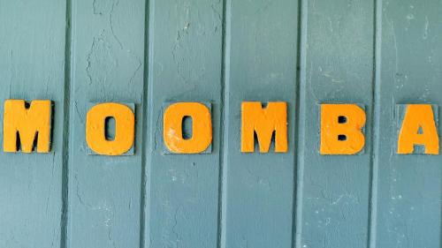 a blue wooden wall with the words monday spelled out in orange letters at Moomba On Main in Wooli