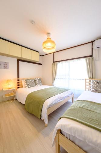 a bedroom with two beds and a window at Cozy 2-Floor Retreat near Ikebukuro - Easy Access to Central Tokyo - アキサポステイ本蓮沼 in Tokyo