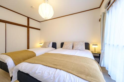two beds sitting next to each other in a bedroom at Cozy 2-Floor Retreat near Ikebukuro - Easy Access to Central Tokyo - アキサポステイ本蓮沼 in Tokyo