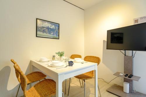 a room with a white table with chairs and a tv at Cozy 2-Floor Retreat near Ikebukuro - Easy Access to Central Tokyo - アキサポステイ本蓮沼 in Tokyo