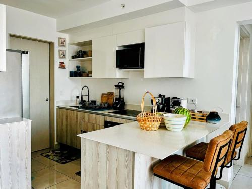 a kitchen with white cabinets and a counter top at Top-floor overlooking uptown with AC & parking in San José