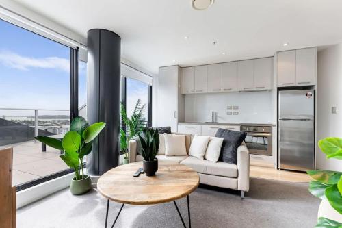 a living room with a couch and a table at Pool, Gym & Modern 2BR Sky Tower View Zodiak Stays in Auckland