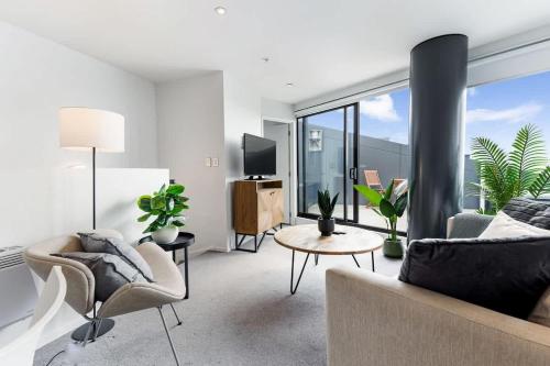 a living room with a couch and chairs and a large window at Pool, Gym & Modern 2BR Sky Tower View Zodiak Stays in Auckland