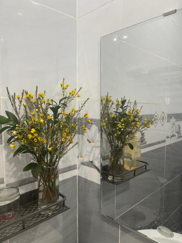 two vases filled with yellow flowers on a shelf at Thương Thương Homestay in Xuan An