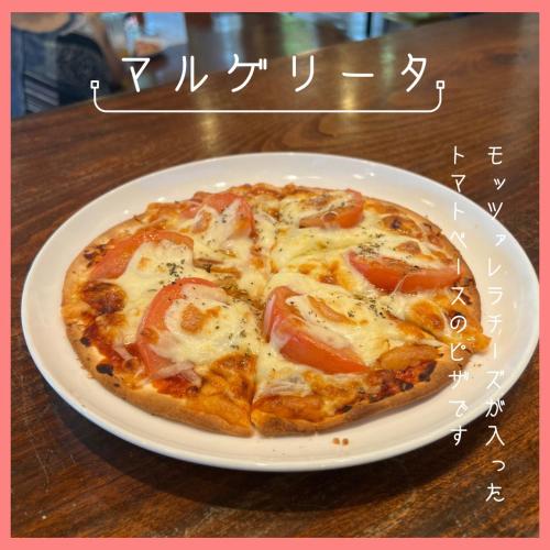 a pizza on a white plate on a table at ペンションニライカナイ NiraiKanai in Awaren