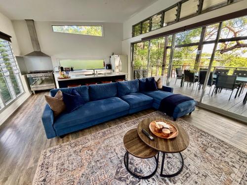 Una sala de estar con un sofá azul y una mesa. en Sandy Escape Holiday House Kingfisher Bay Resort, en Kingfisher Bay