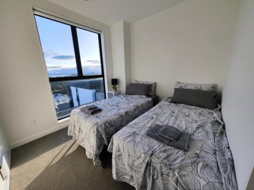 a bedroom with two beds and a large window at Auckland Birkenhead BNB in Auckland
