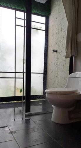 a bathroom with a toilet and some windows at House Viotá in Viotá