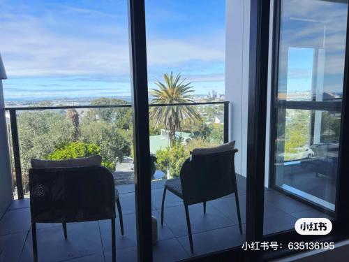 a room with two chairs and a large window at Auckland Birkenhead BNB in Auckland