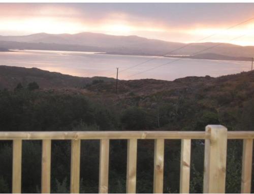 a view of a body of water behind a fence at Sunrise Mist Cottage in Garinish West