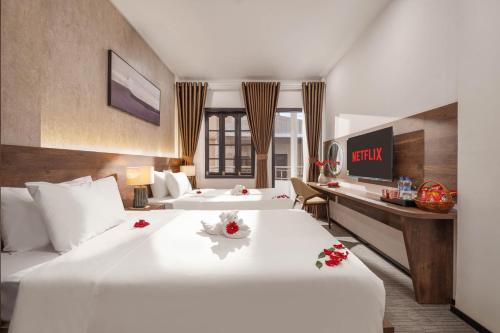 ein Hotelzimmer mit zwei Betten und einem Schreibtisch in der Unterkunft Kly Luxury Hotel in Hue