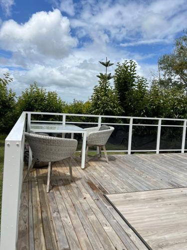 a deck with a table and two chairs on it at Twinkle Orchard Camp in Taupaki