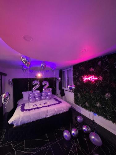 une chambre avec des lumières violettes et un lit avec des ballons dans l'établissement Secret room, au Havre