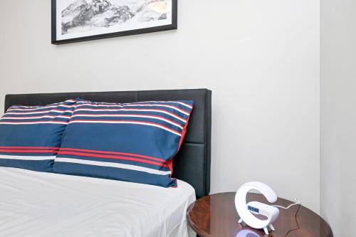 a bed with a blue and red striped pillow and a table at Home away from Home in Victoria