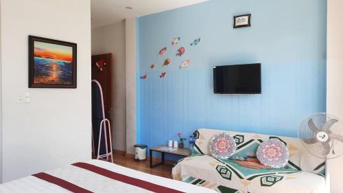 a bedroom with a blue wall with a couch and a tv at NEST House in Ấp Kim Thạch