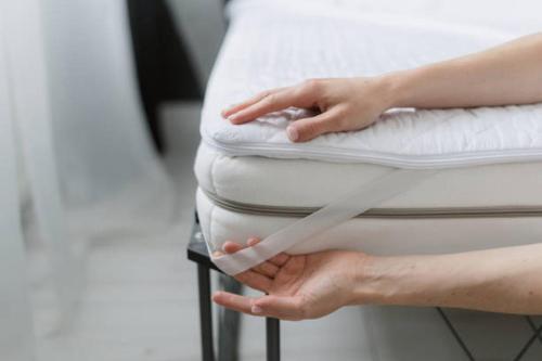 a woman is putting her hand on a pillow on a bed at yourcity 台北101 和 大巨dome旁邊 大空間睡8人 in Taipei