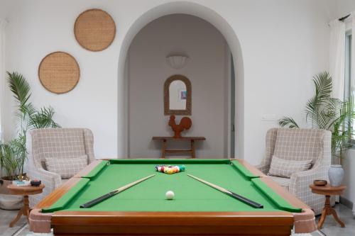 a pool table in a living room with two chairs at Villa Mandarina by The Blue Kite - 4BHK Standalone Luxuxy Villa in Assagao with Large Private Pool, Pool Table, Kids Play Area, Garden, Caretaker & Security in Siolim