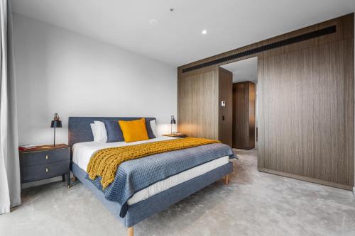 a bedroom with a large bed with yellow pillows at Collins House Apartments by CLLIX in Melbourne