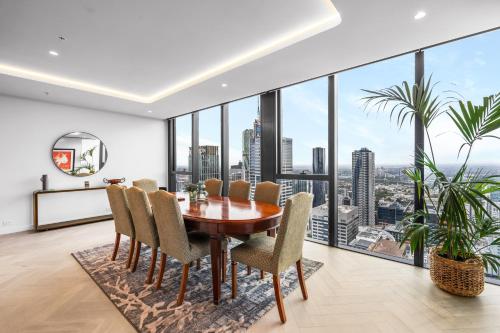 a dining room with a table and chairs and large windows at Collins House Apartments by CLLIX in Melbourne