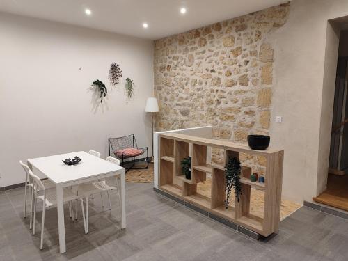 un salon avec une table blanche, une table et un mur en pierre dans l'établissement 2 bedroom house, à Talence