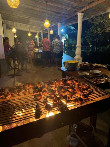 a group of people standing around a grill with food at Seth Villa by Magampura Resorts in Tangalle