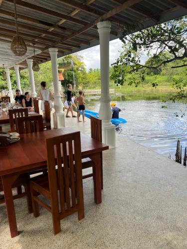 a group of people sitting at a table by the water at Seth Villa by Magampura Resorts in Tangalle