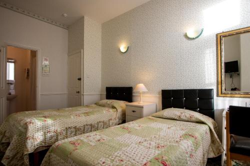 a bedroom with two beds and a mirror at The Carlton Hotel in Folkestone