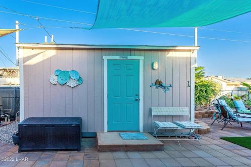 a small house with a blue door and a chair at NEW Pool Spa Firepit Pool Table Sleeps 12 in Lake Havasu City