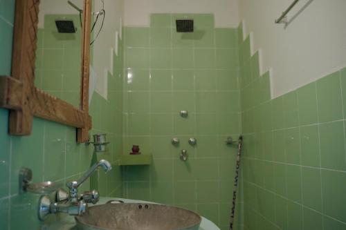 a green tiled bathroom with a sink and a mirror at Sapana Village Lodge in Sauraha
