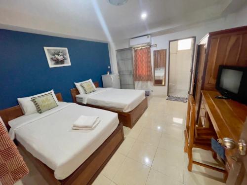 Una habitación de hotel con dos camas y un televisor. en Wellington Apartment, en Ban Nong Waeng