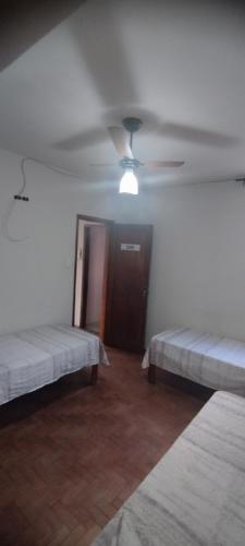 a room with two beds and a ceiling fan at Hospedaria Central in Lavras