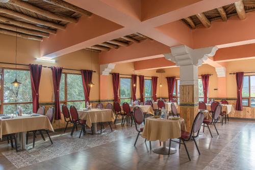 a dining room with tables and chairs and windows at Echor Mud Huts Tabo, Spiti Valley in Kaza