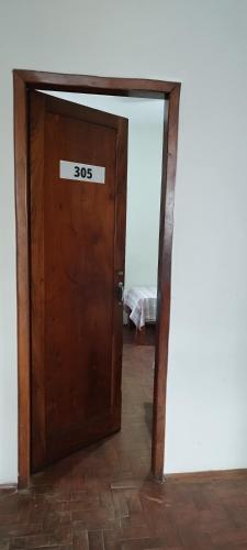 a wooden door with a sign on it at Hospedaria Central in Lavras