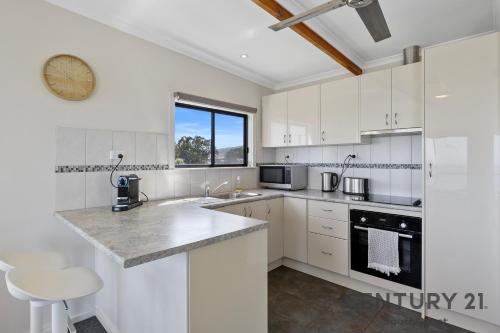 eine Küche mit weißen Schränken und einem großen Fenster in der Unterkunft See-Sea House - Sellicks Beach - C21 SouthCoast Holidays in Sellicks Beach