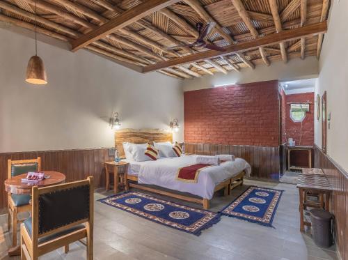 a bedroom with a bed and a brick wall at Echor Mud Huts Tabo, Spiti Valley in Kaza