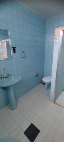 a blue bathroom with a sink and a toilet at Hospedaria Central in Lavras
