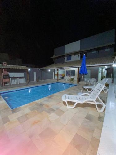a pool at night with two lounge chairs and a umbrella at Suítes da lagoa monte alto in Arraial do Cabo