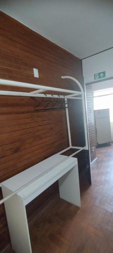 a white desk in a room with a wooden wall at Hospedaria Central in Lavras